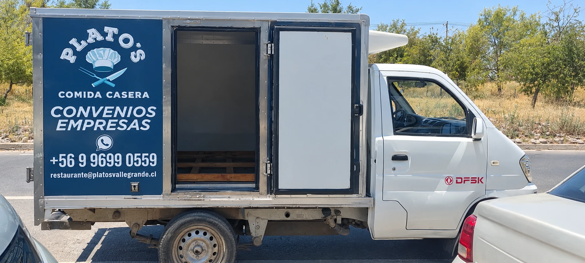 Camión refrigerado de reparto de Plato's, con el logo y los datos de contacto en el costado